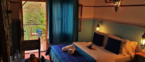 Un dormitorio con cama, mesita de noche, lámpara de pared y vistas al exterior.