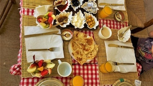Un bufé de desayuno con diversos platos, utensilios y un mantel a cuadros.