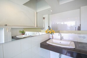 A modern bathroom with a large mirror, a sink, and a shower.