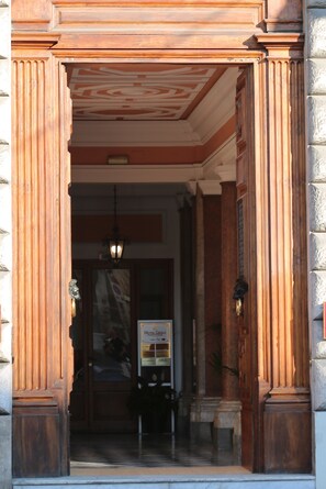 Entrada de hotel con fachada de madera, un candelabro y un cartel.