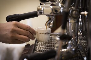 Una mano sosteniendo una taza debajo de una máquina de café espresso.