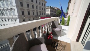 A balcony with wicker chairs and a doormat reading "ESPIONNE PALACE HOTEL".