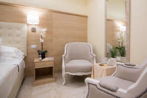 Una habitación de hotel con cama, una silla, una mesita de noche, una mesa con lámpara y un espejo.