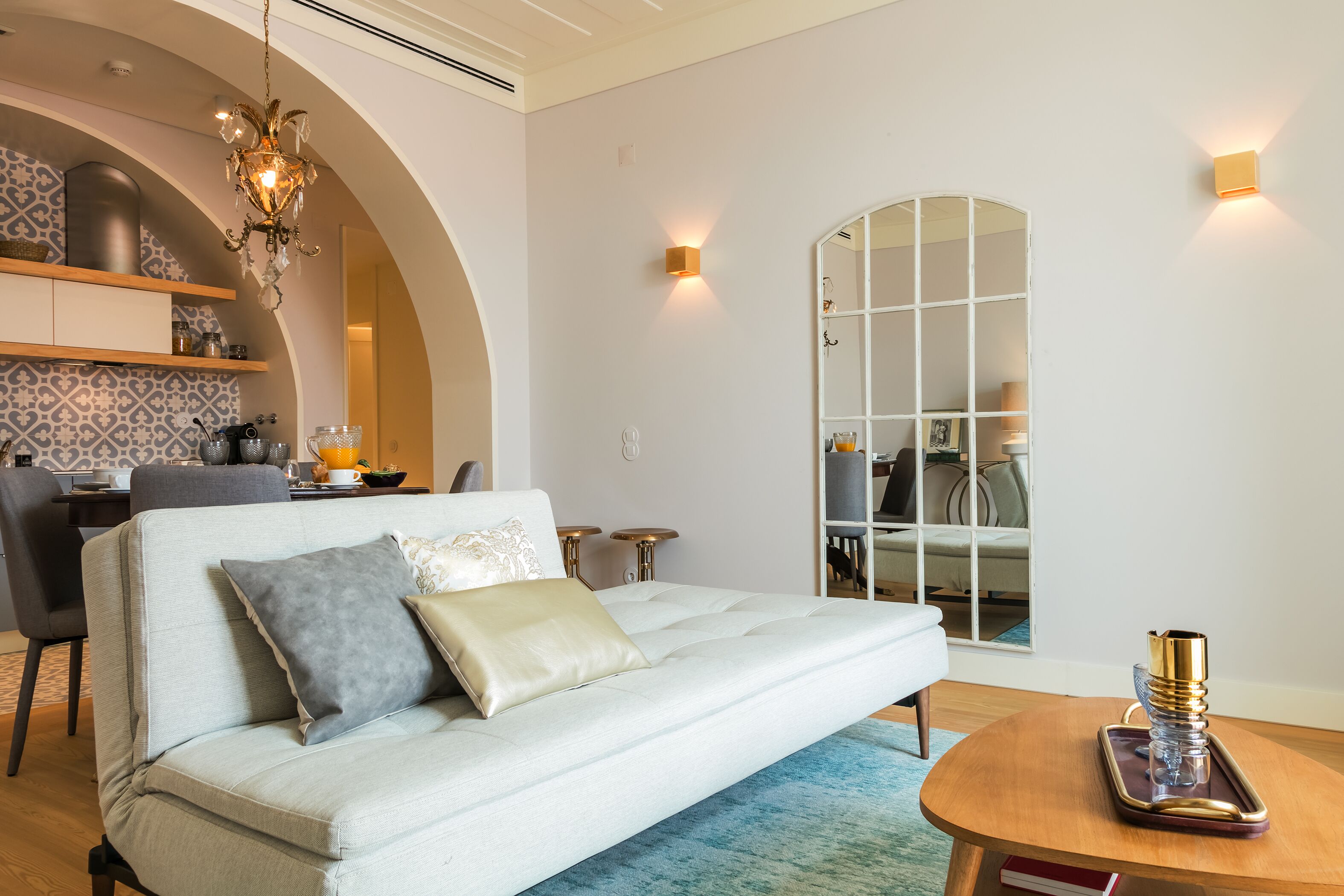 Ein modernes Wohnzimmer mit einem hellen Sofa, einem Holztisch und einer Kandelaberleuchte.
