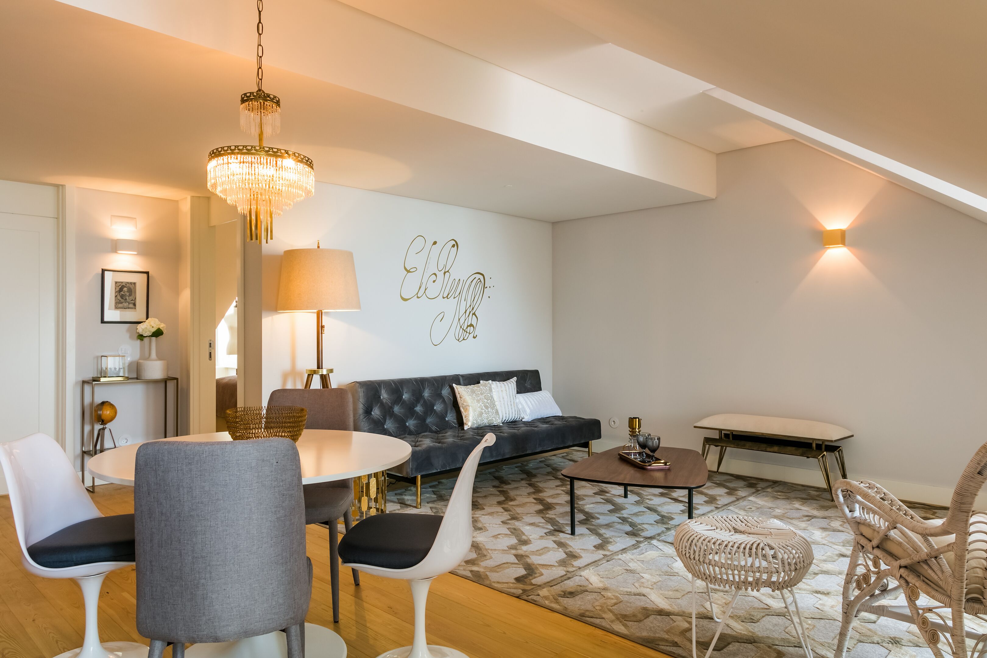 Un salon moderne avec un canapé, des fauteuils, une table basse et un lustre.