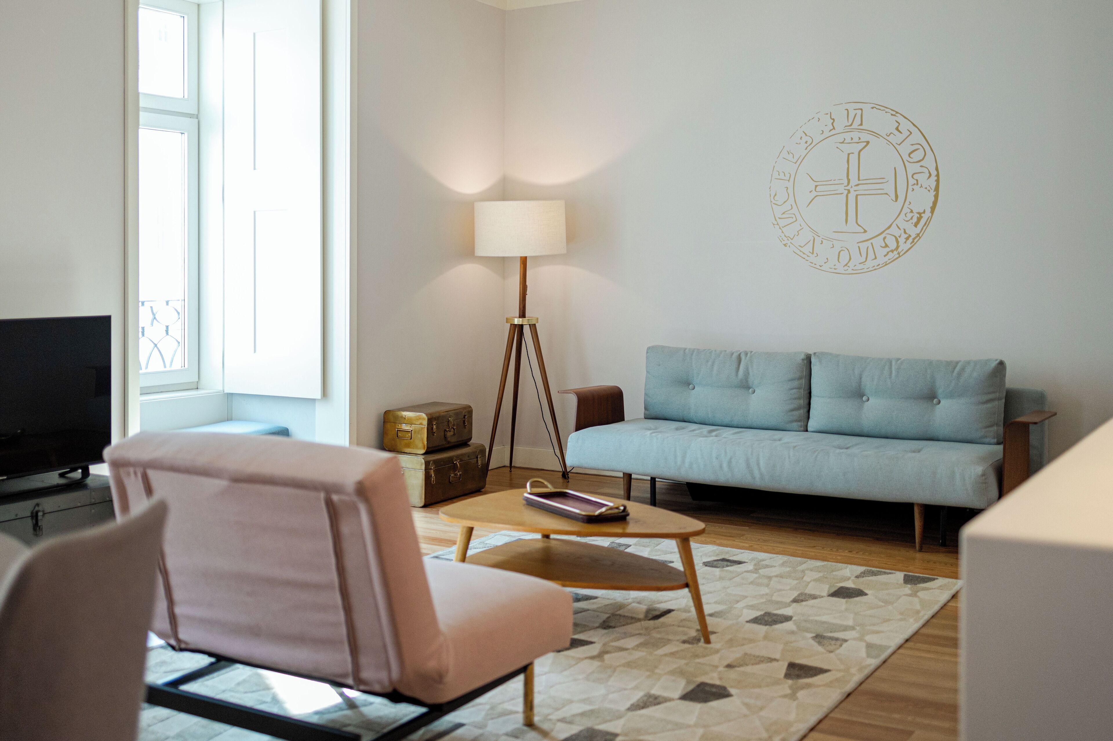 Un salon moderne comprenant un canapé, un fauteuil, une lampe sur pied et un téléviseur.