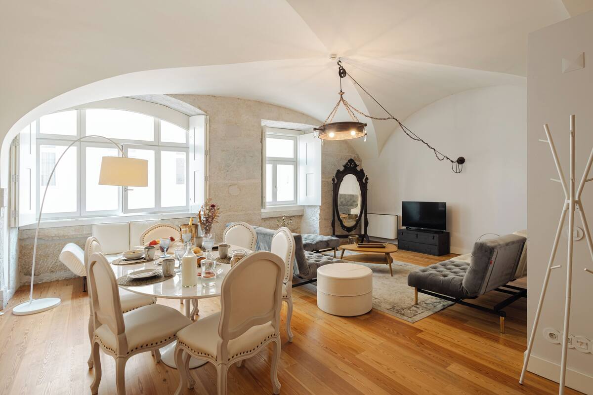 A spacious living room with a dining area, a large mirror, and a television.