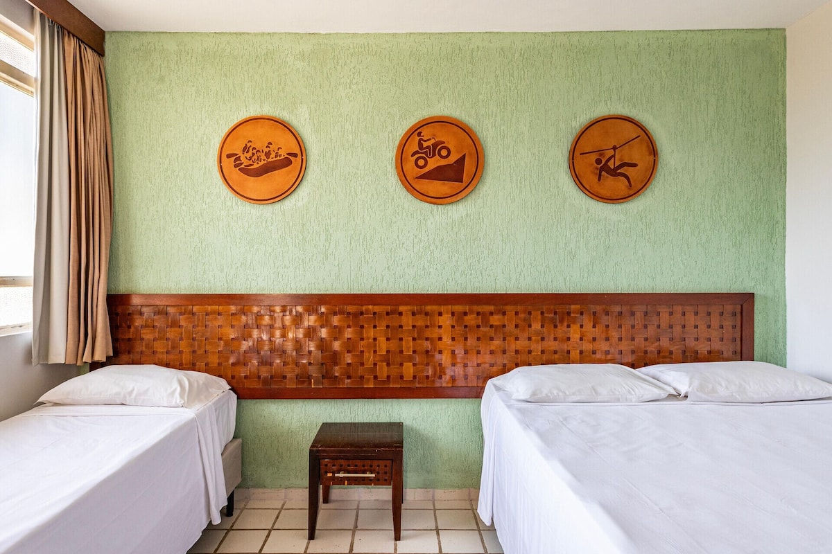 Quarto de hotel com duas camas, uma cabeceira de tecido e três decorações circulares na parede.