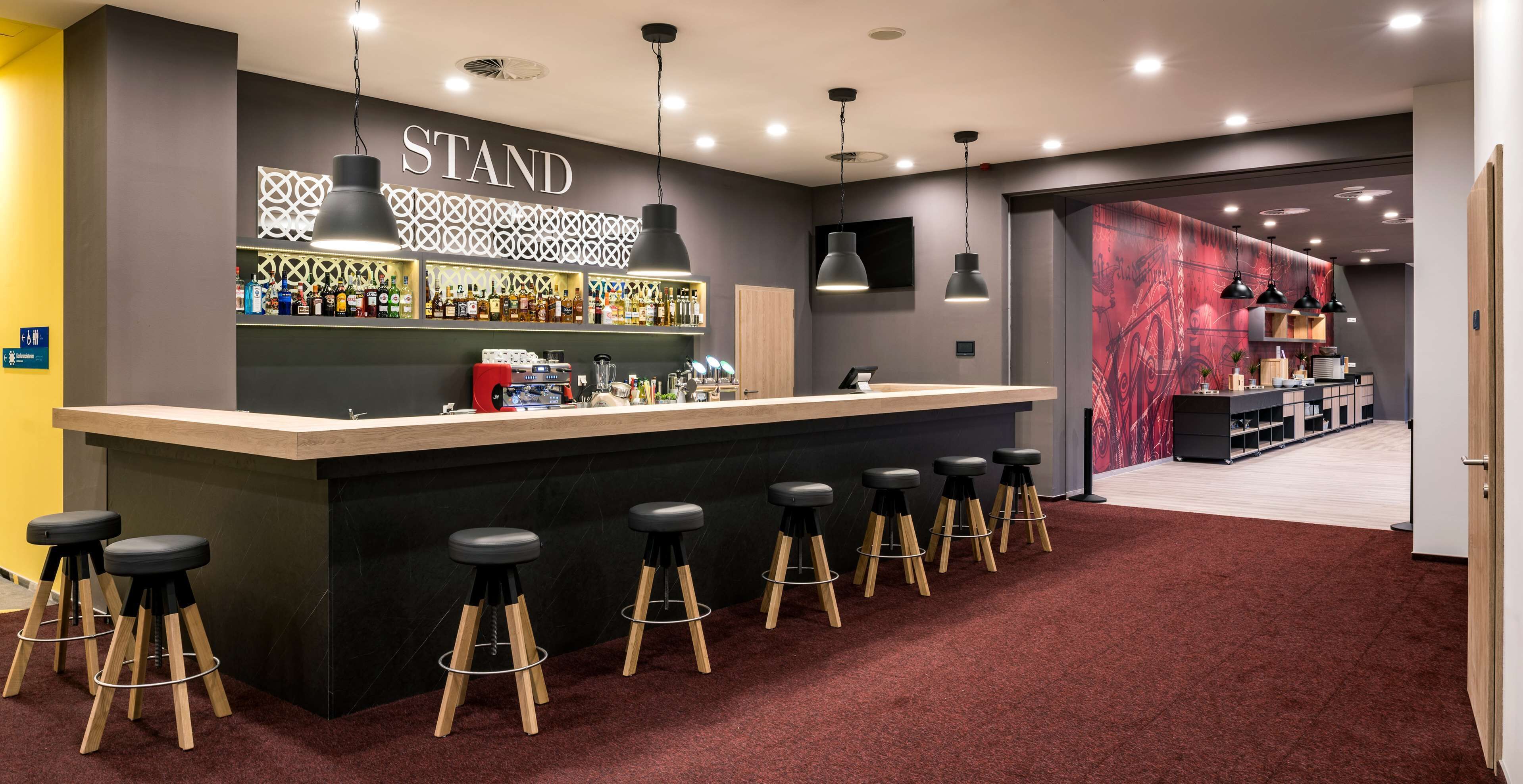 Zona de bar con mostrador, taburetes y un cartel que dice 'STAND'.
