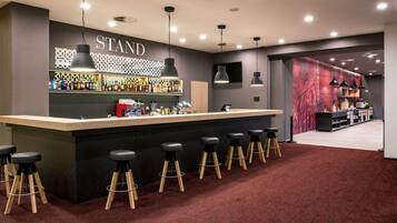 Zona de bar con mostrador, taburetes y un cartel que dice 'STAND'.
