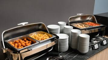 Ein reichhaltiges Buffet mit Speisenplatten, gestapelten Tellern und Geschirr.
