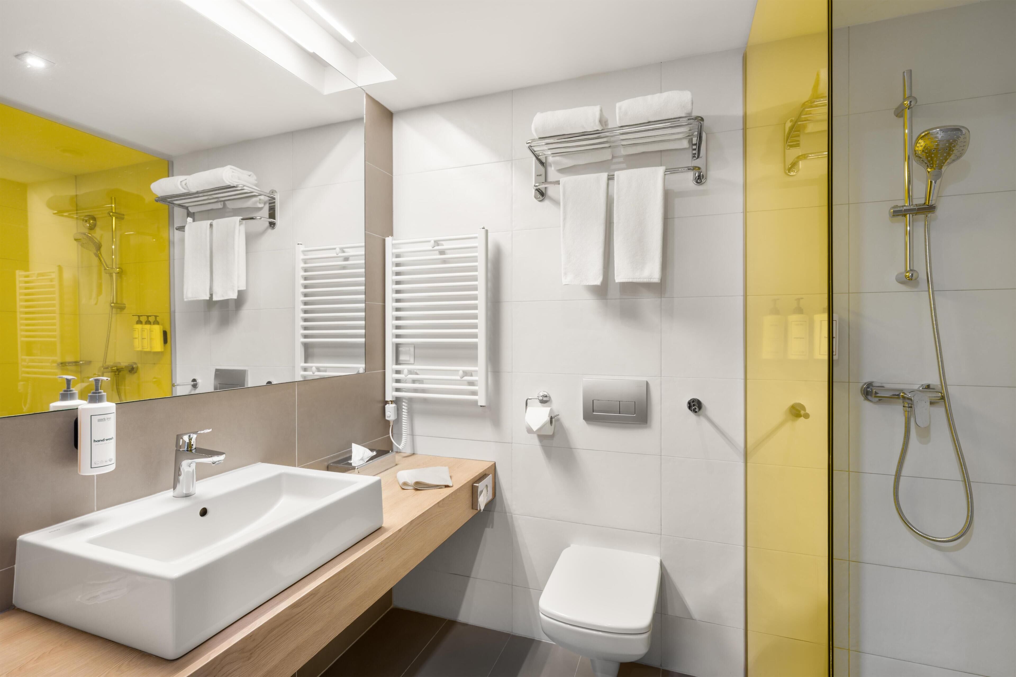Een moderne badkamer met een groot wastafel, toilet en douche.