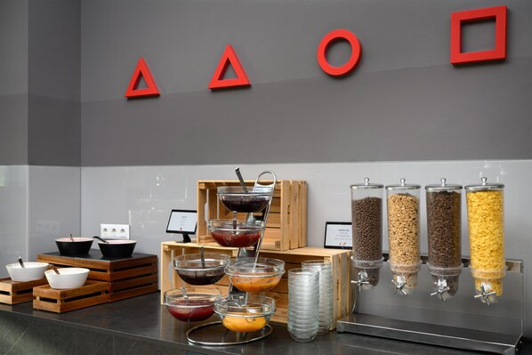 A buffet setup with various food containers and bowls, a wooden crate, and a wall with geometric shapes. - Park Inn by Radisson Hotel and Spa Zalakaros (Zalakaros)