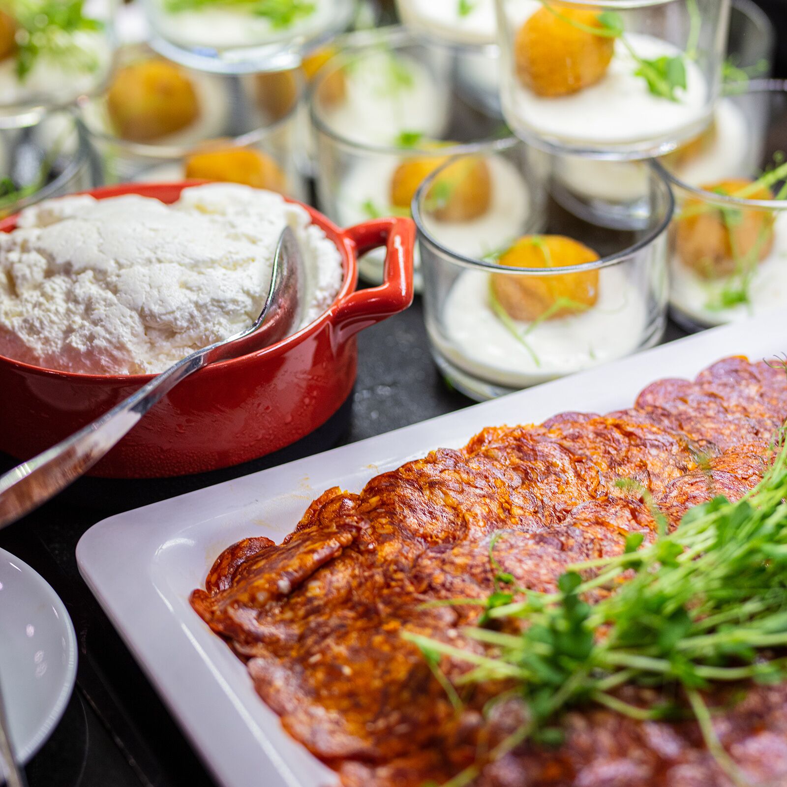 A variety of food items including a large piece of meat, bowls of flour, and glasses with creamy contents.