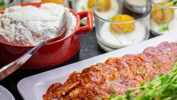 A variety of food items including a large piece of meat, bowls of flour, and glasses with creamy contents.
