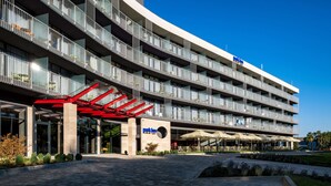 Un hotel de varios pisos con un diseño moderno, con balcones, una zona de estar exterior cubierta y una entrada destacada.