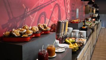 Un bufé con muffins, fruta y bebidas.