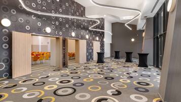 A modern interior with patterned carpet, wooden doors, and a seating area with orange chairs.