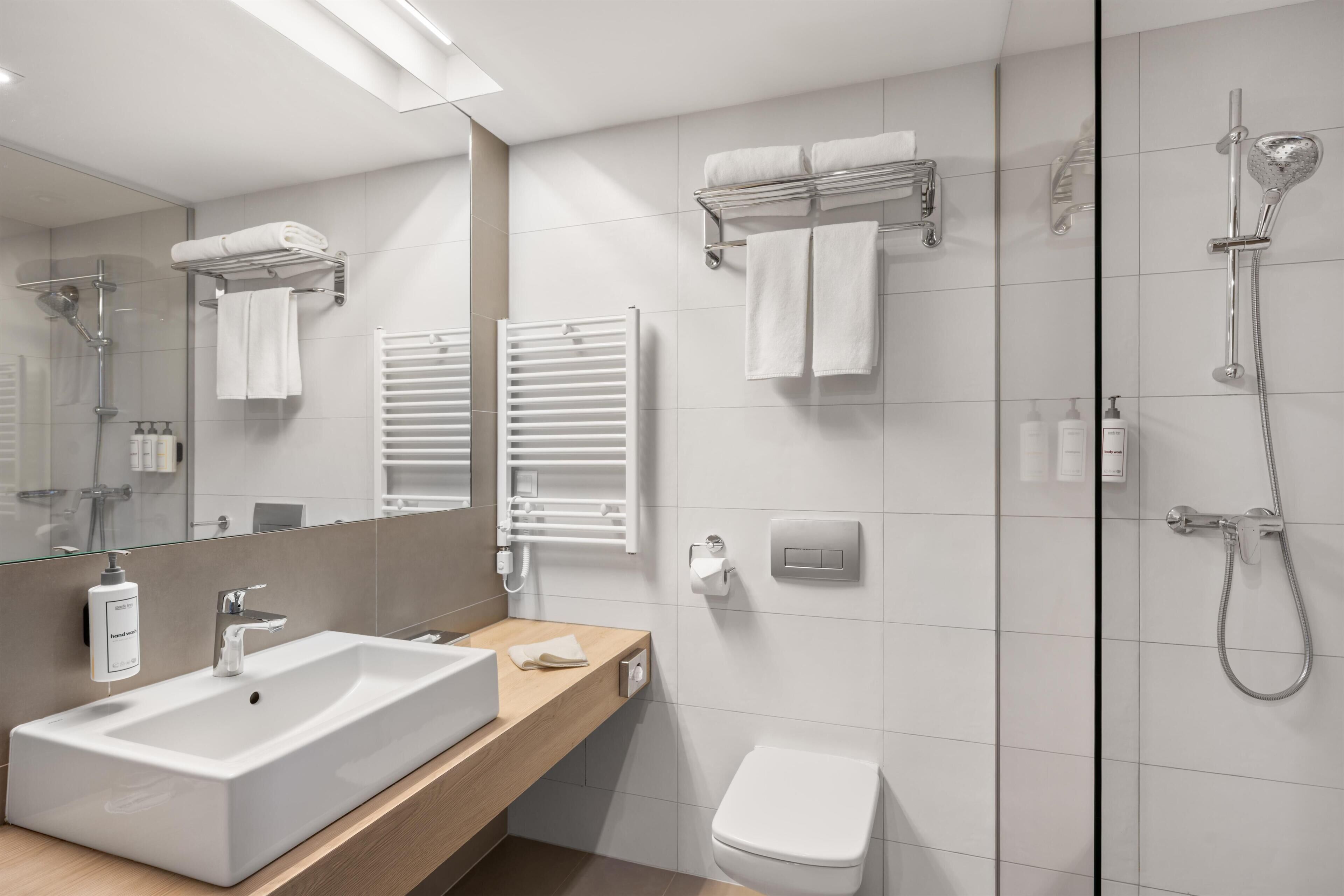 A modern bathroom with a large sink, a toilet, a shower, and a mirror.