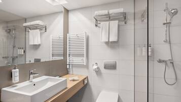 A modern bathroom with a large sink, a toilet, a shower, and a mirror.