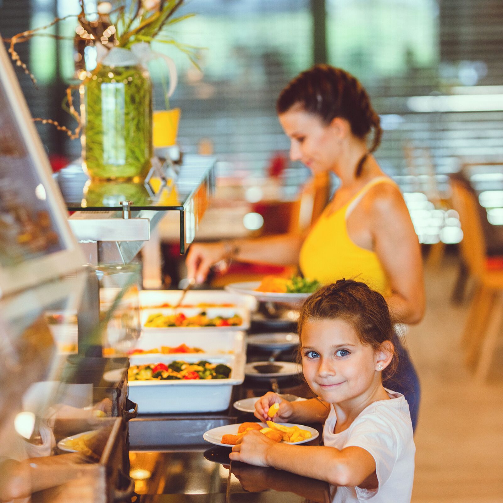 A buffet setup with various food items and a person serving.