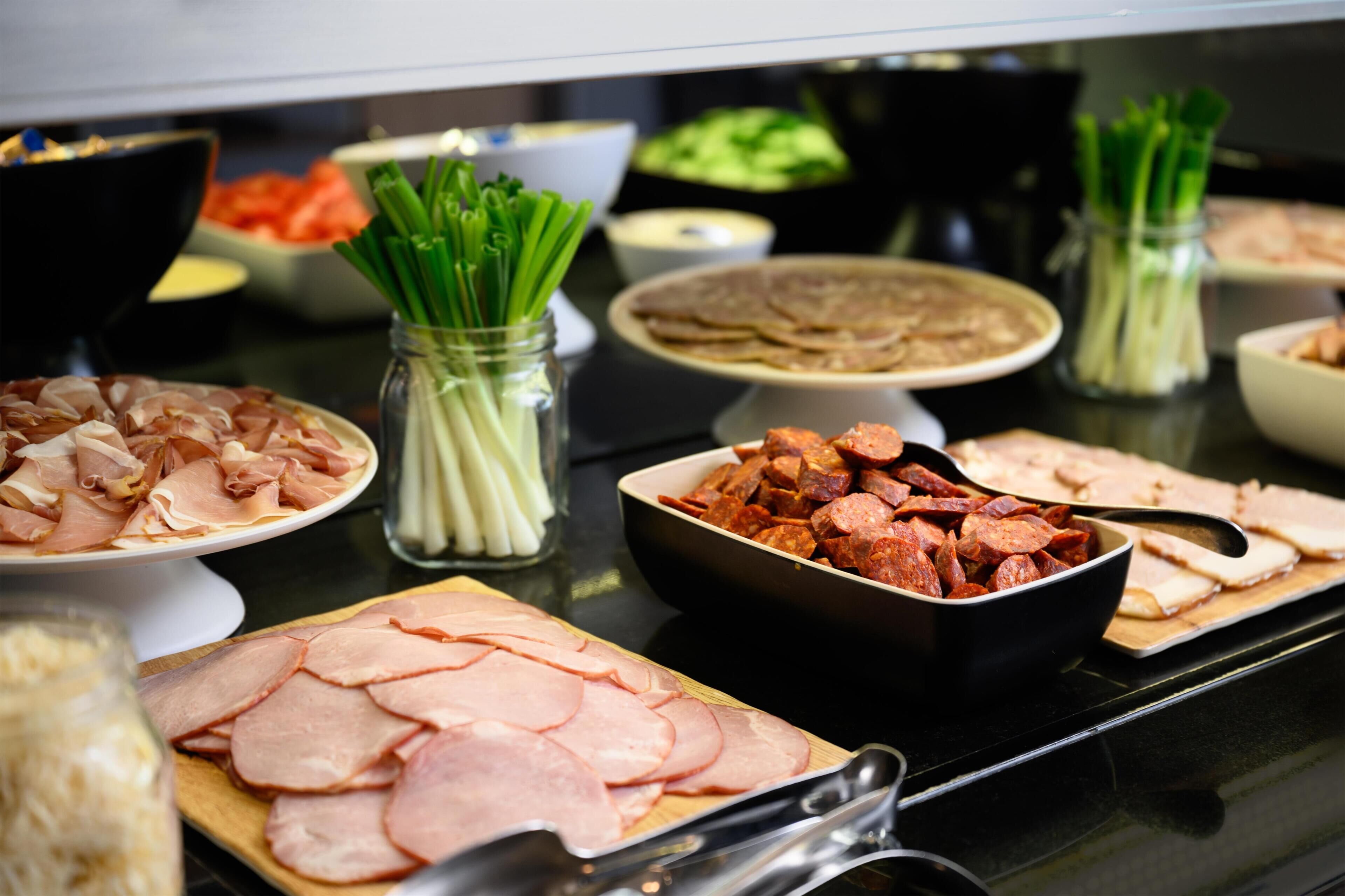 Ein Buffet mit verschiedenen Speisen, darunter Aufschnitt, Gemüse und weitere Gerichte.