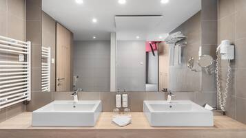 A modern bathroom with two sinks, a large mirror, and a towel rack.