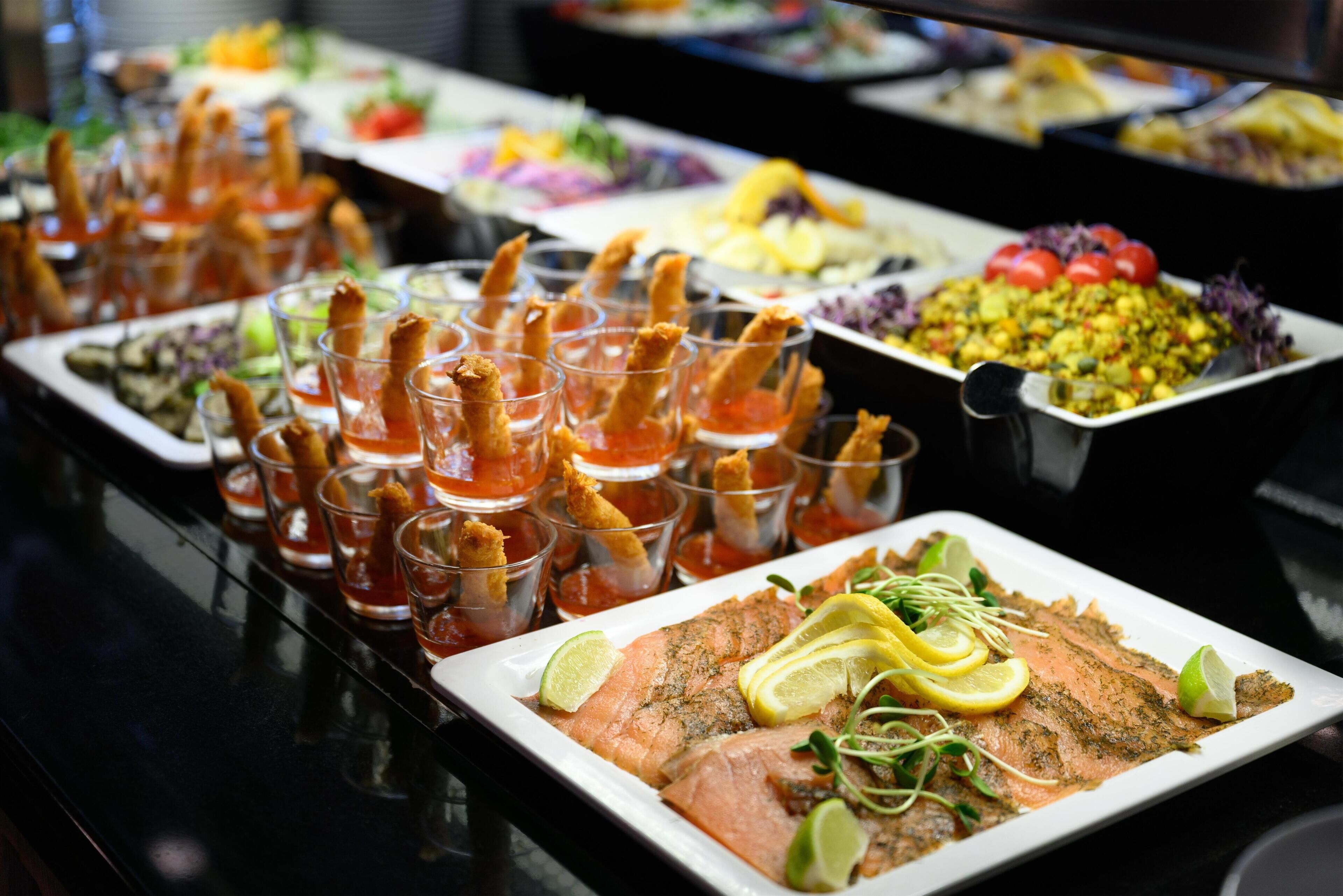 A buffet with various dishes including salmon, salad, and appetizers.