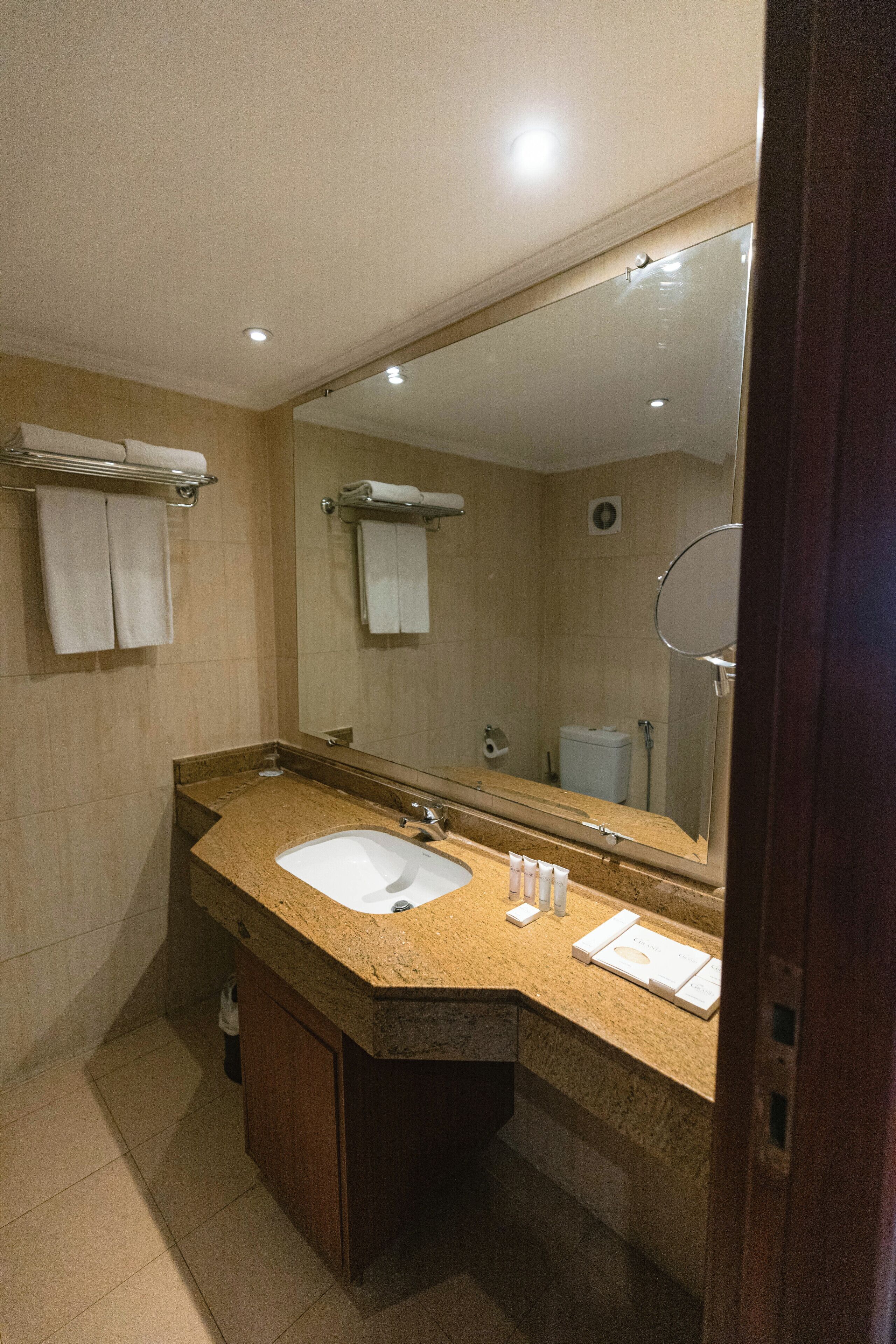 Un baño con lavamanos, espejo, toallero y retrete.
