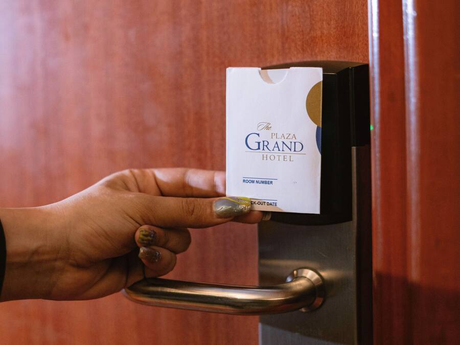 Une main insérant une carte à puce dans la serrure d’une porte.