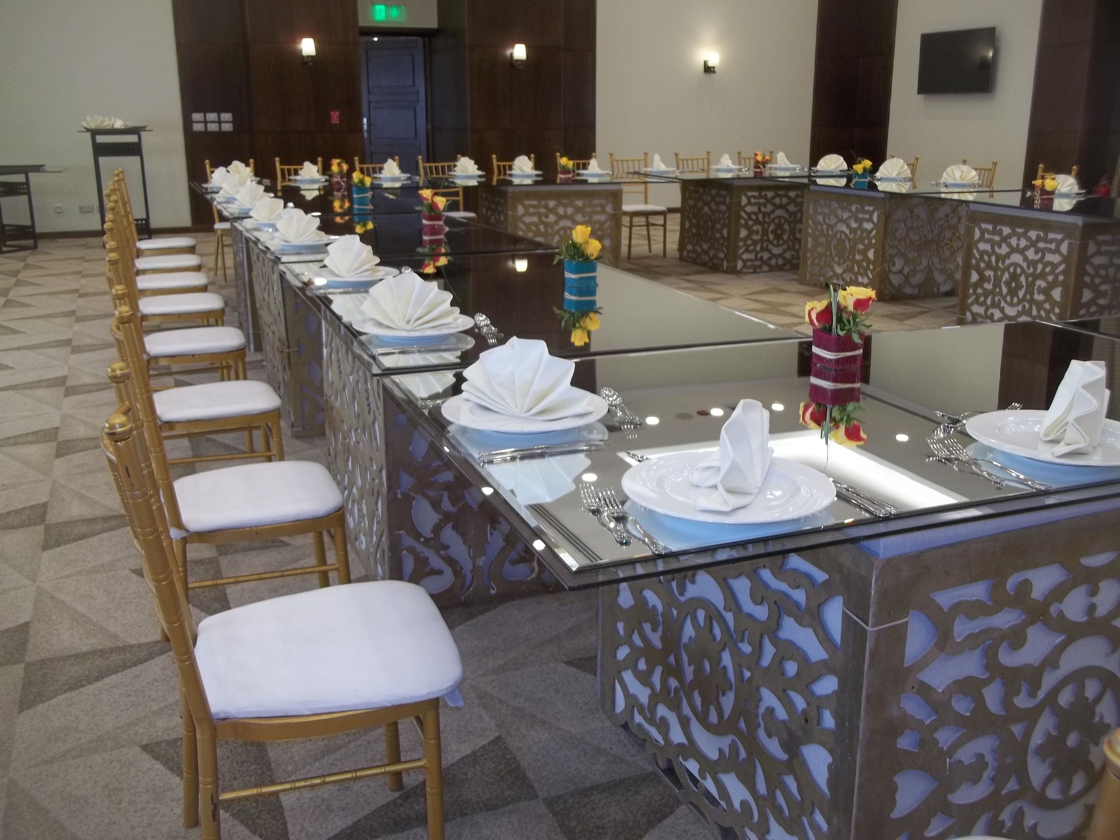 A long banquet table with white napkins, silverware, and floral centerpieces.