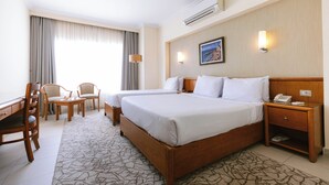 A hotel room with a large bed, two bedside tables, a desk with a chair, a small table with chairs, and a large window with curtains. - The Grand Plaza Hotel Smouha (Alexandria)