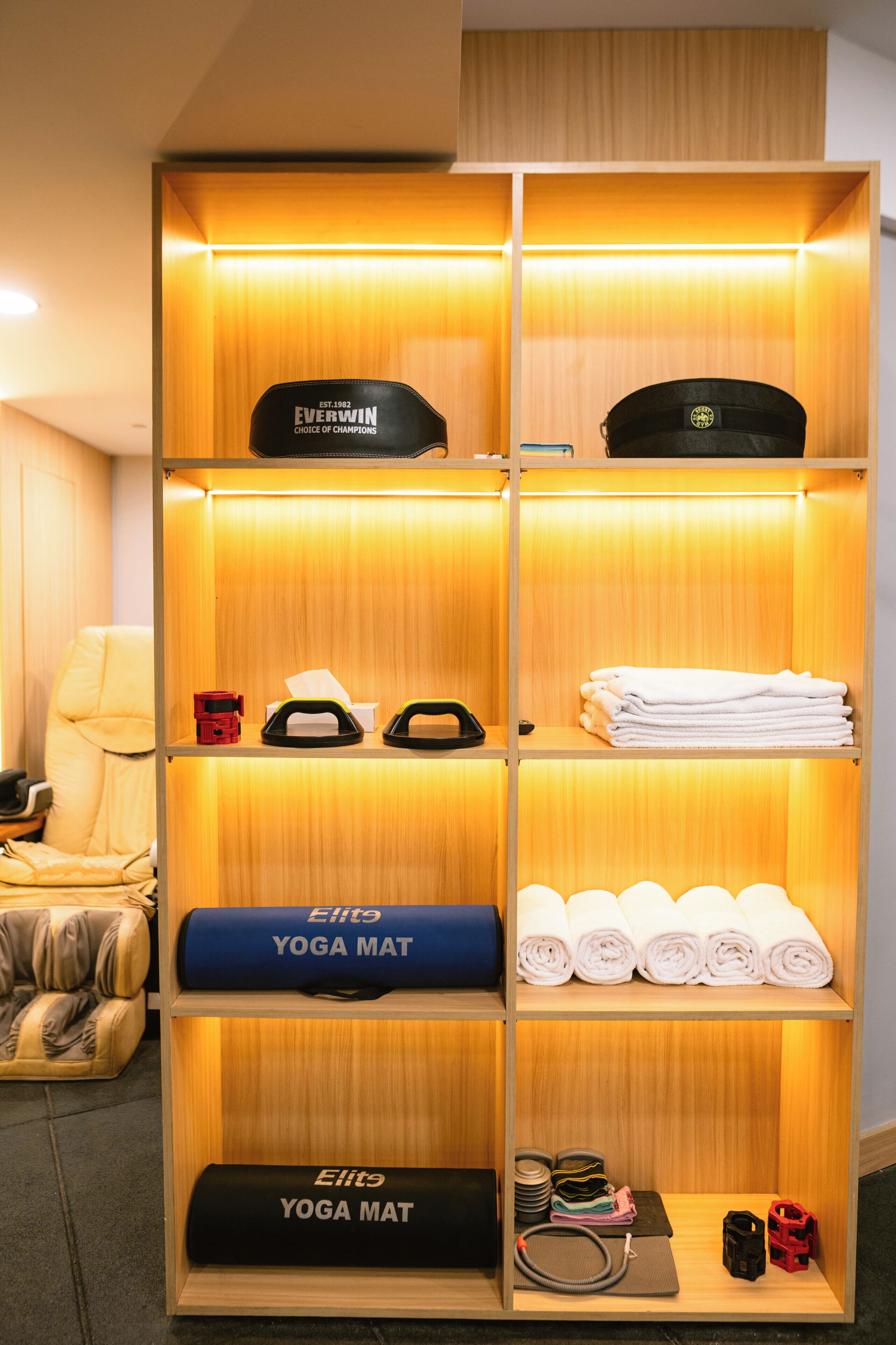 A neatly organized storage unit with shelves containing yoga mats, towels, and a cap.