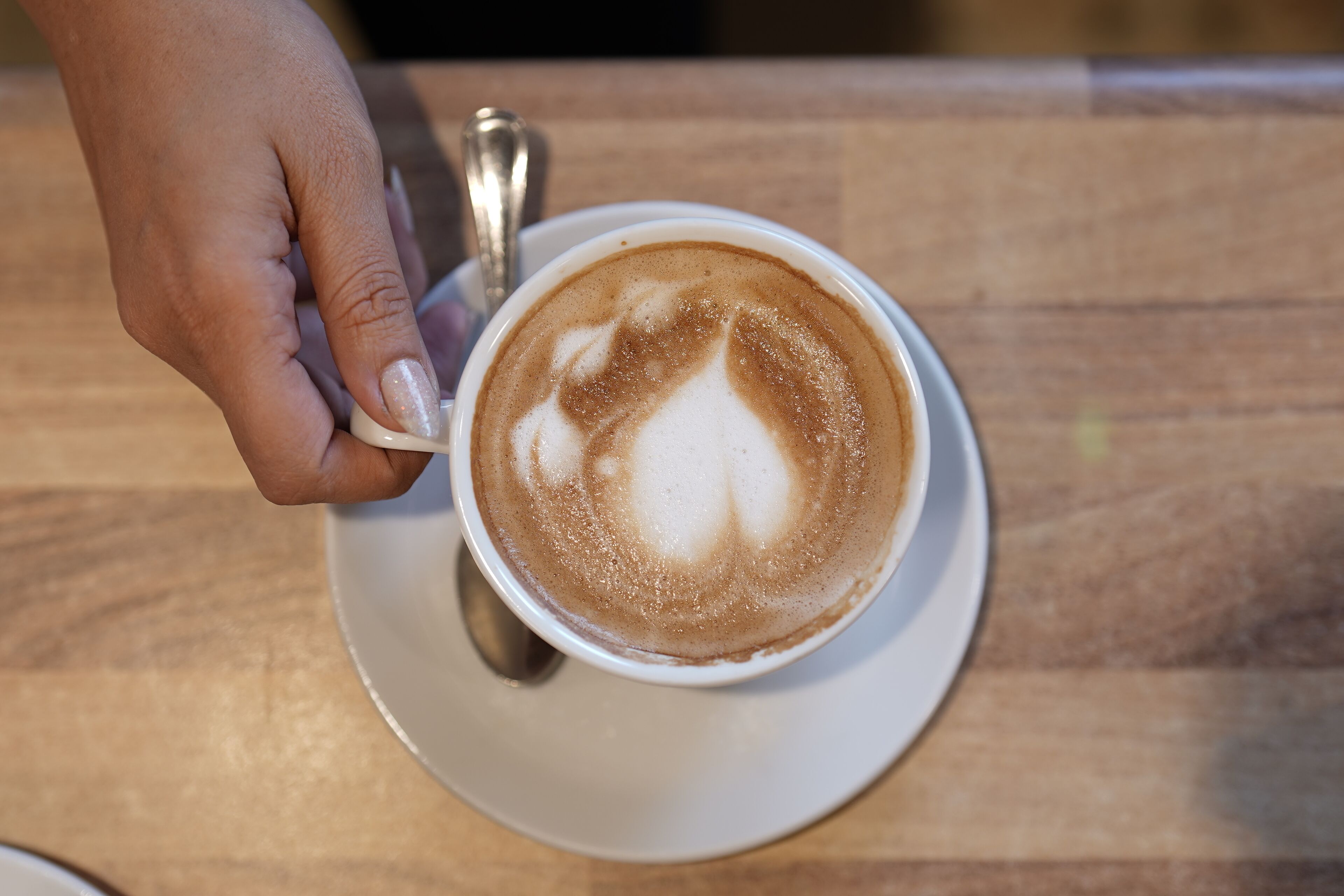 A cup of coffee with latte art on a saucer.