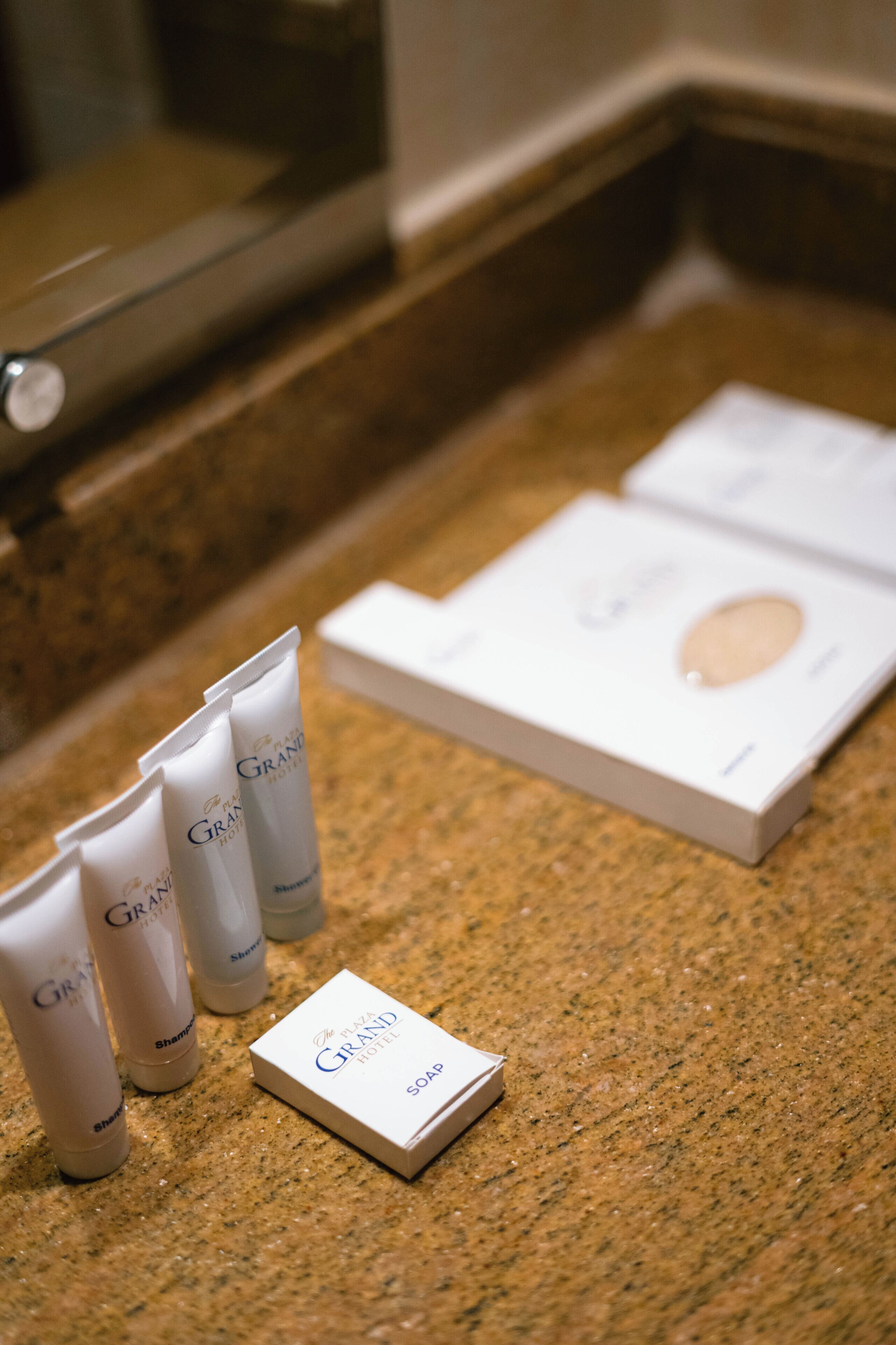 Uma bancada de banheiro com produtos de higiene, incluindo um sabonete em barra e vários frascos de shampoo.