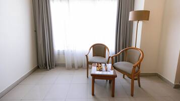 A room with two wooden chairs, a small table with a tray, and a floor lamp.