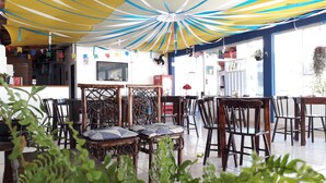 A restaurant with a high ceiling, striped ceiling fans, and a variety of seating options including wooden chairs and tables. - Pousada Porto Marola (Ipojuca)