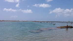 A beach with clear water and a rocky outcrop. - Pousada Porto Marola (Ipojuca)