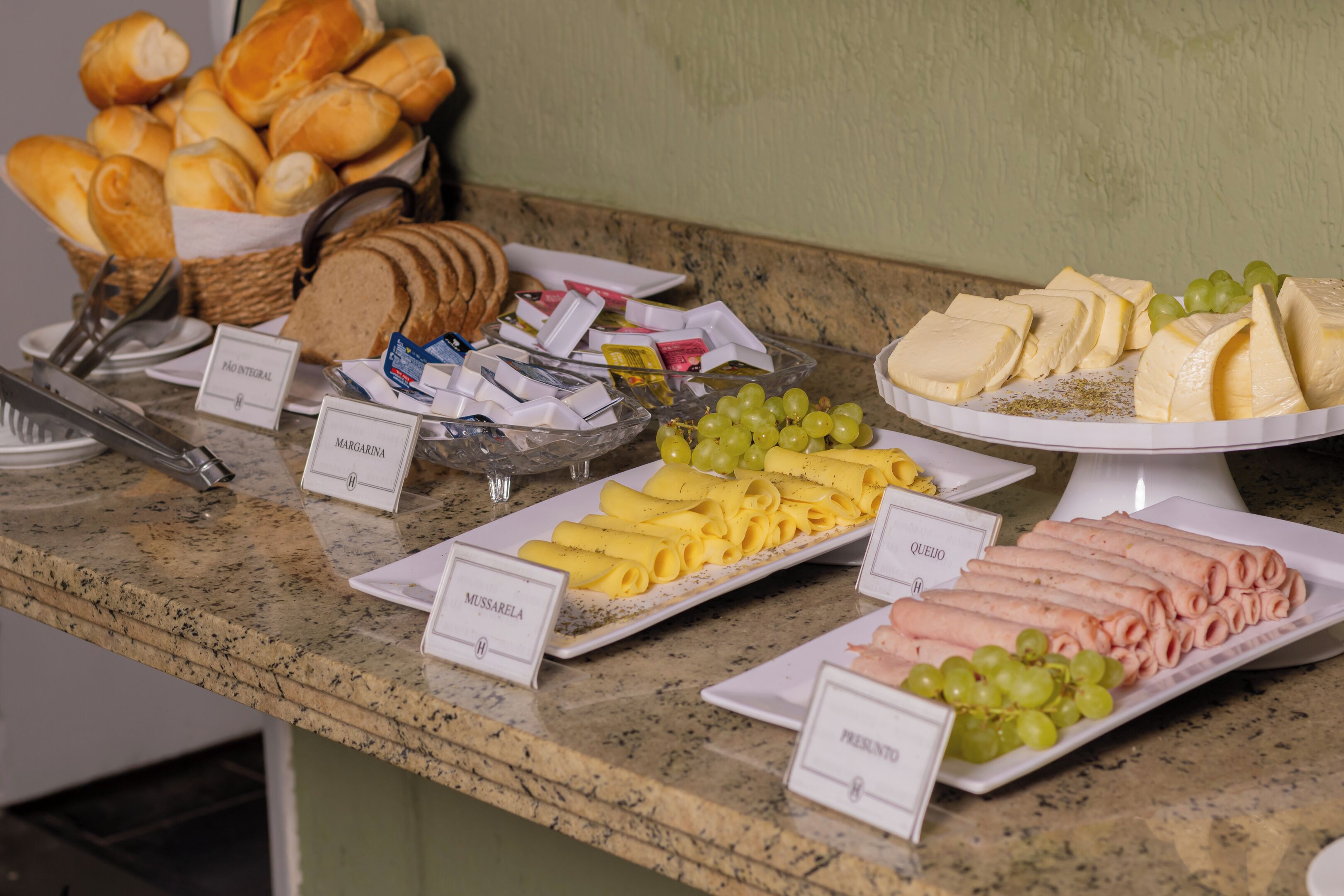 A buffet with labeled food items including bread, cheese, and grapes.
