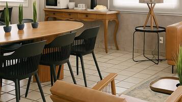 Una sala de estar moderna con una mesa de comedor de madera, sillas negras, un sofá marrón y una pequeña mesita de noche con una lámpara.