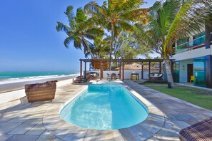 Una piscina al aire libre, sombrillas, sillones reclinables de piscina