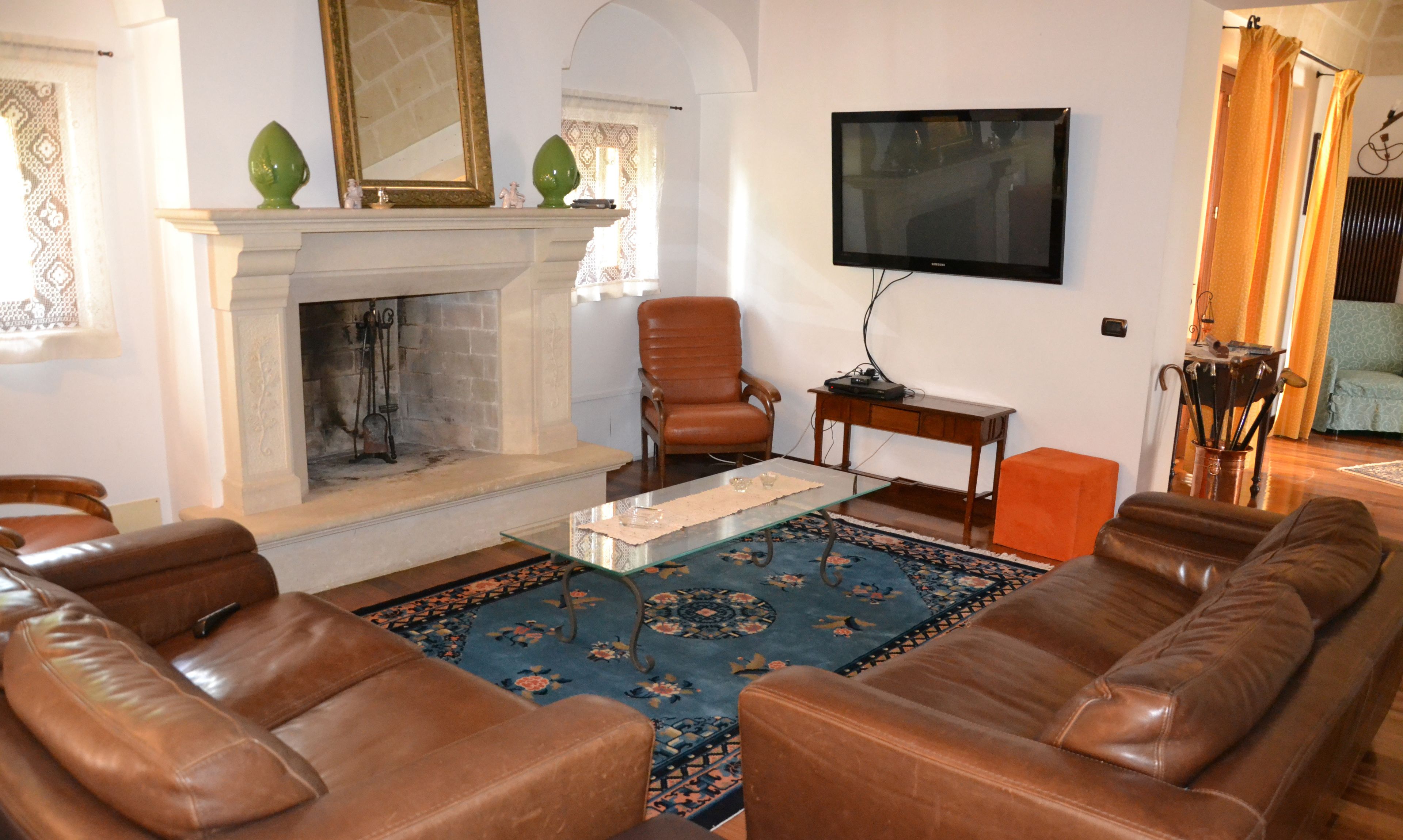 Un salón con sofás de cuero, chimenea, televisor de pantalla plana y alfombra estampada.