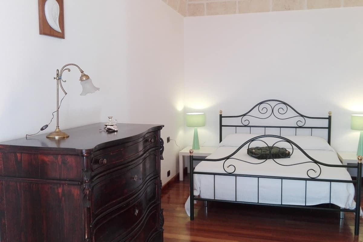 A bedroom with a wooden dresser, a metal bed frame, and two bedside lamps.