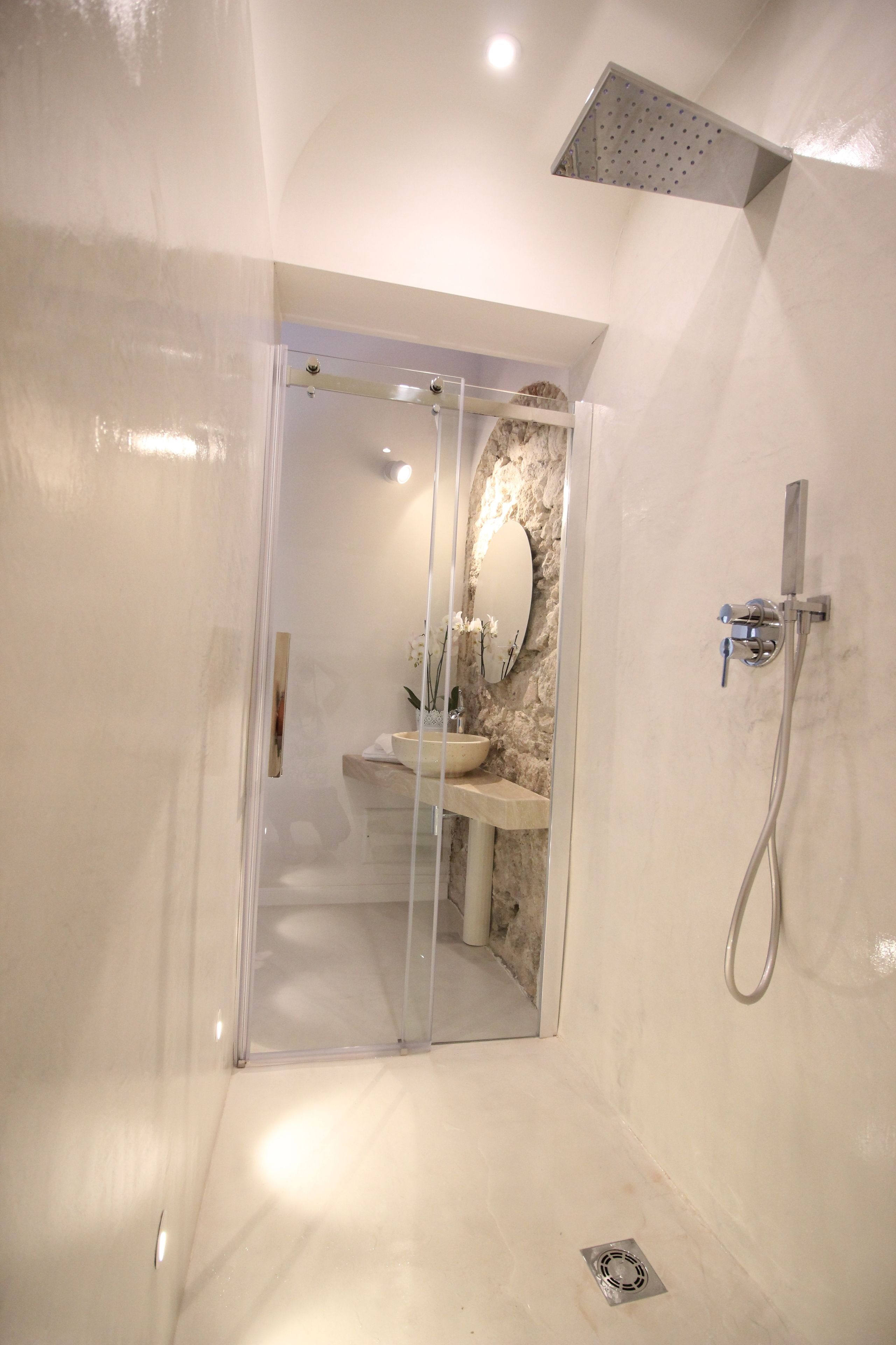 Une salle de bain moderne avec une douche à parois de verre, un lavabo en marbre et un miroir fixé au mur.