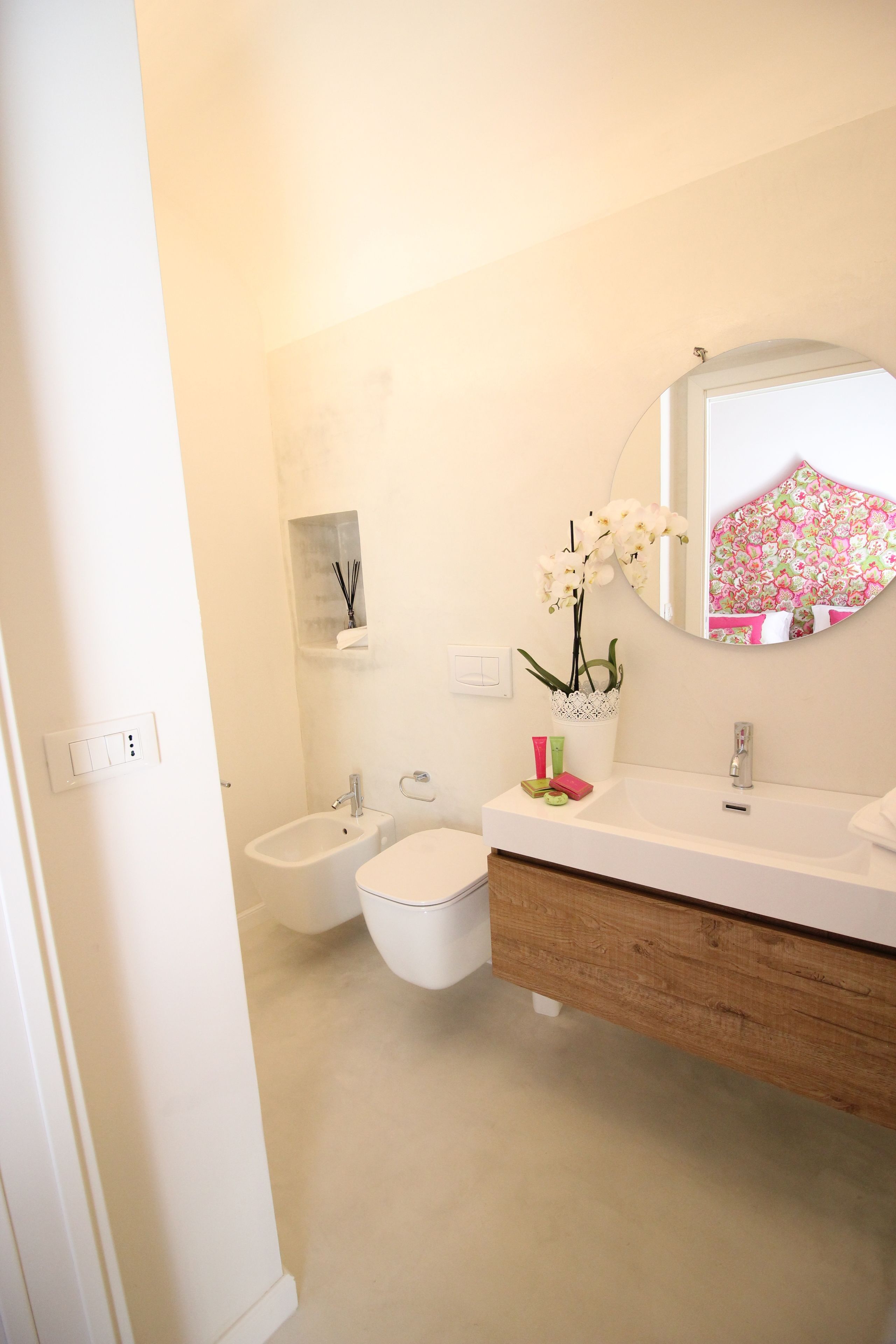 A bathroom with a white sink, a bidet, a toilet, and a mirror with a floral frame.