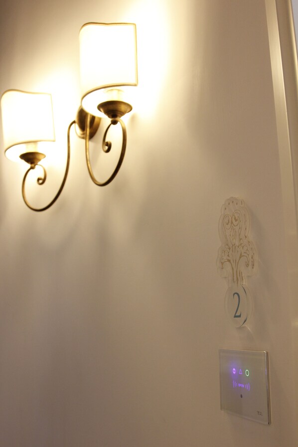 Un luminaire mural doté de deux lampes, d’une plaque décorative portant le chiffre « 2 » et d’un panneau de commande avec des indicateurs lumineux.
