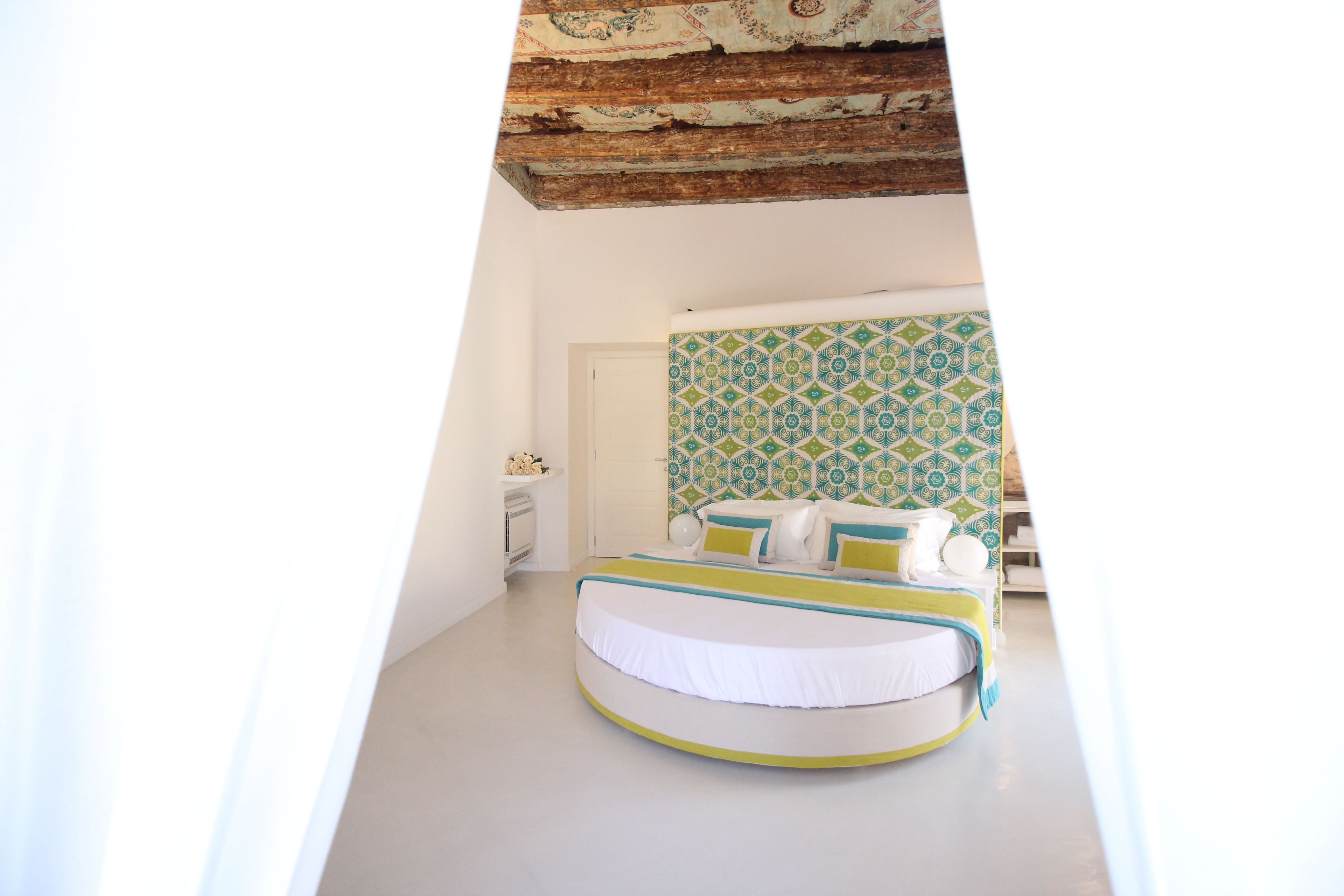 Una camera da letto con un letto rotondo, un muro decorato e un soffitto in legno.