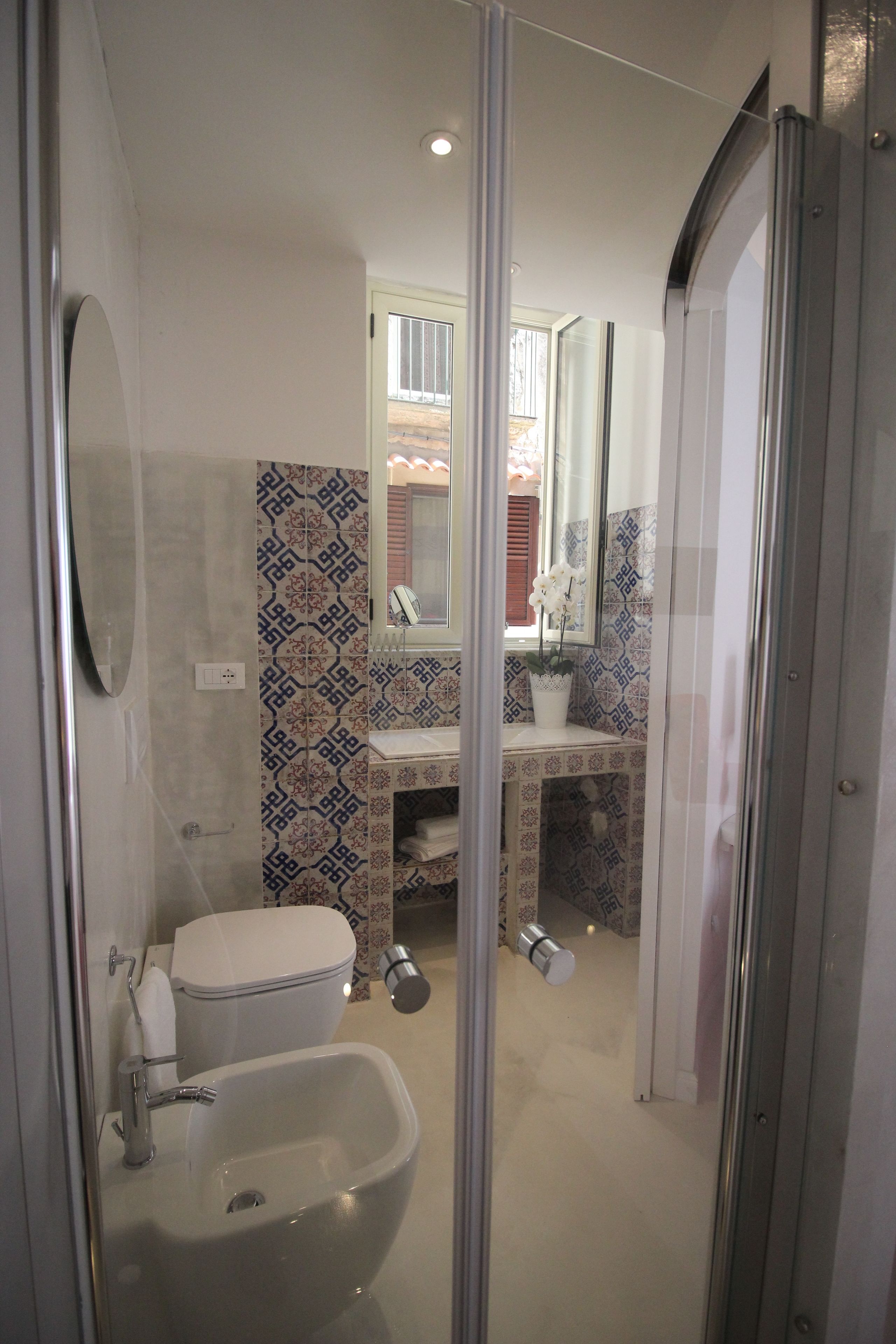 A modern bathroom with a glass shower enclosure, a white sink, and a toilet.