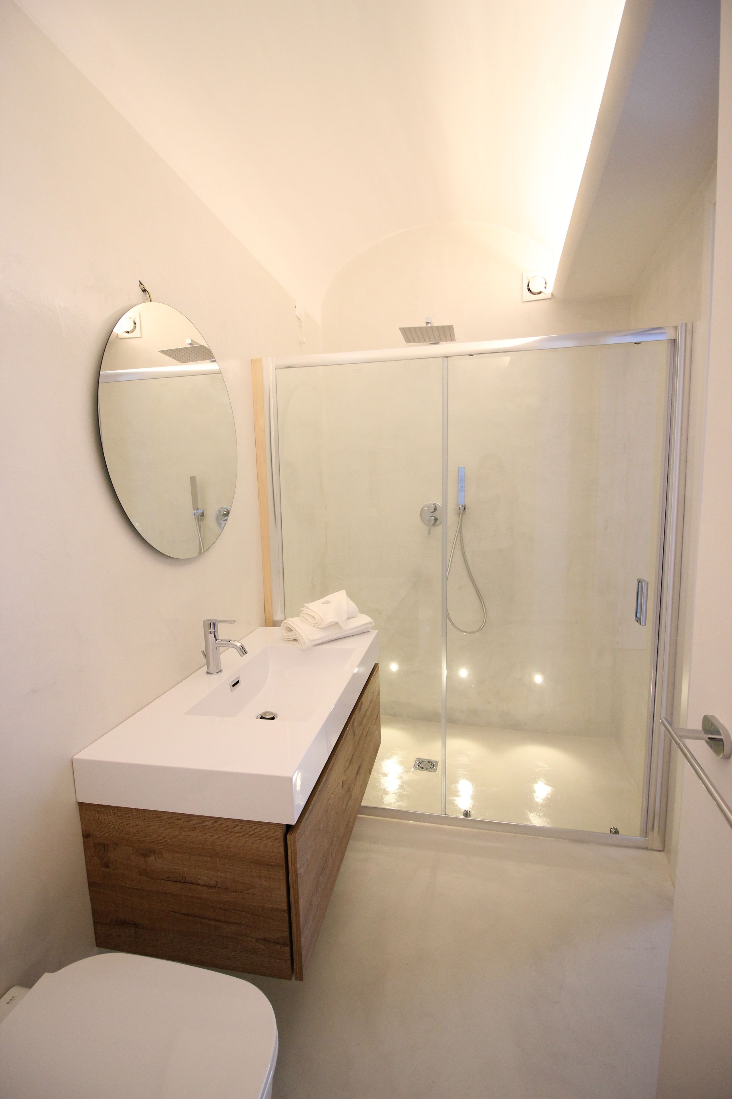 Une salle de bain moderne avec un lavabo blanc, un miroir et une cabine de douche.