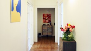 Ein Flur mit Holzboden, weißen Wänden und einer Blumenvase auf einem Schrank.